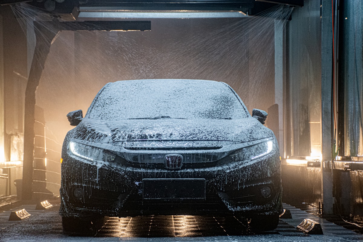 Thick white foam being worked over a car's paint by hand